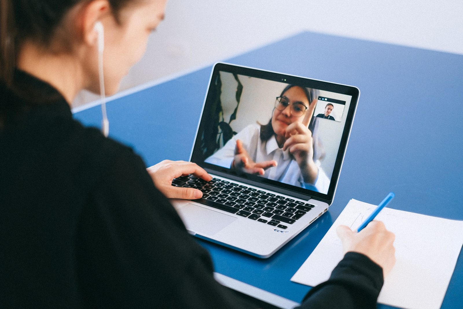 Una empleada sigue un curso en línea en su laptop y toma notas.