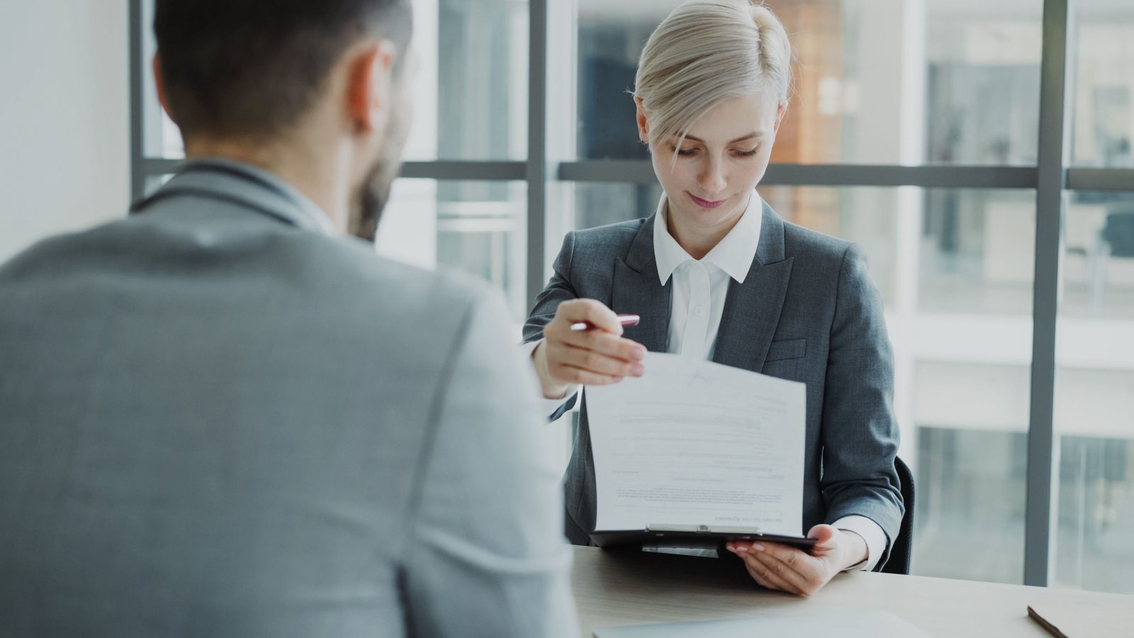 Dos profesionales revisan un contrato en una oficina moderna.